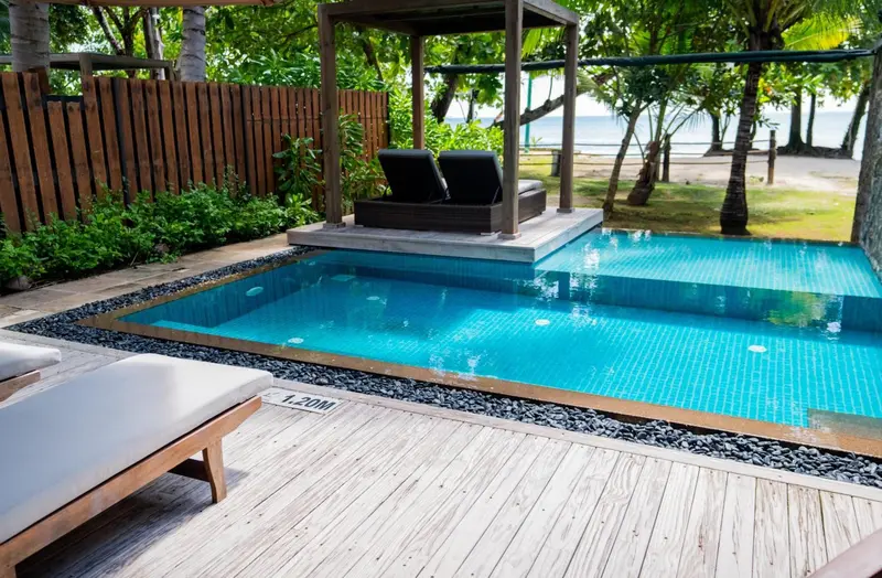 Une piscine privee avec terrasse et mobilier de jardin.