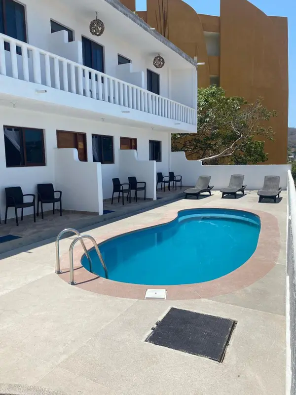 Une piscine rectangulaire est entourée d'un espace aménagé avec des chaises longues et des tables basses.