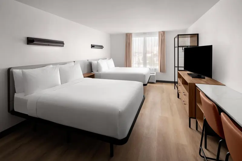 Une chambre lumineuse avec deux lits simples et un espace bureau.