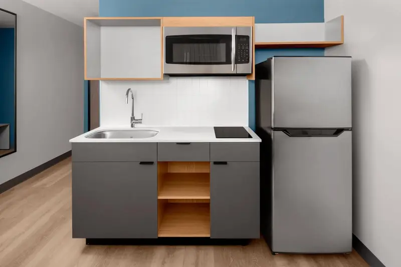 Une kitchenette moderne avec un évier, des plaques de cuisson et un réfrigérateur.
