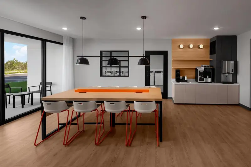 Une salle lumineuse avec une longue table et des chaises.