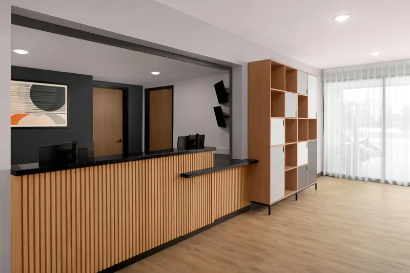 Un comptoir d'accueil en bois clair dans un hall d'hôtel moderne.