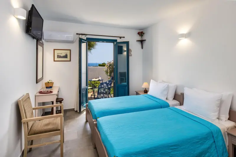 Une chambre lumineuse avec deux lits simples et une vue sur la mer.