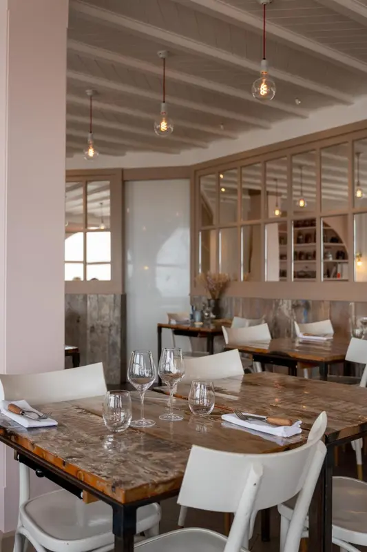 Une table est dressée dans une salle lumineuse avec des suspensions.