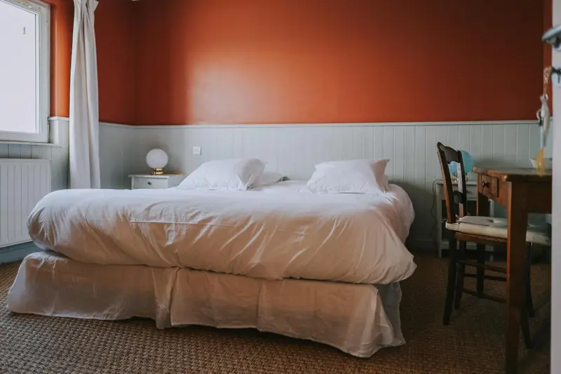 Une chambre lumineuse avec un lit fait et une table de chevet.