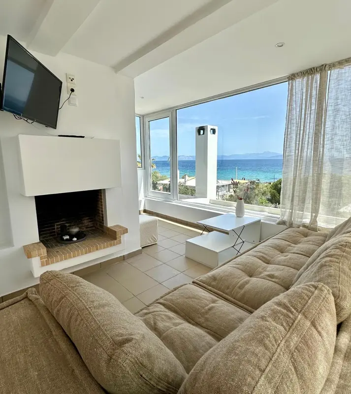 Espace de détente lumineux avec canapé et vue sur la mer.