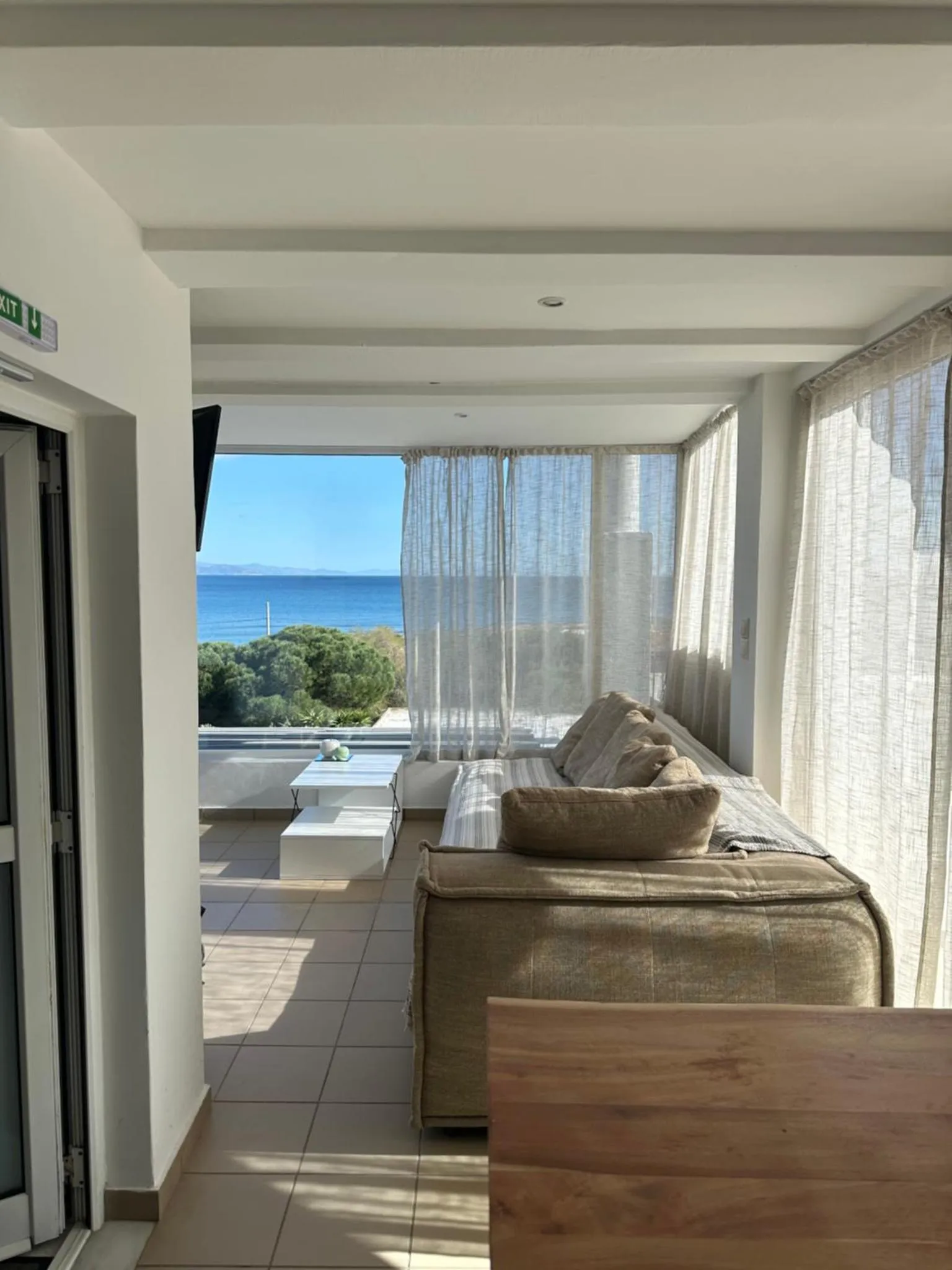 Espace de détente lumineux avec canapé et vue sur la mer.