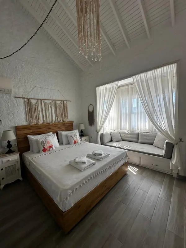 Une chambre lumineuse avec un grand lit et un coin salon près d'une fenêtre.