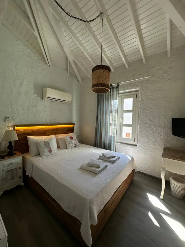 Chambre lumineuse avec un lit recouvert de draps blancs et un éclairage chaleureux.