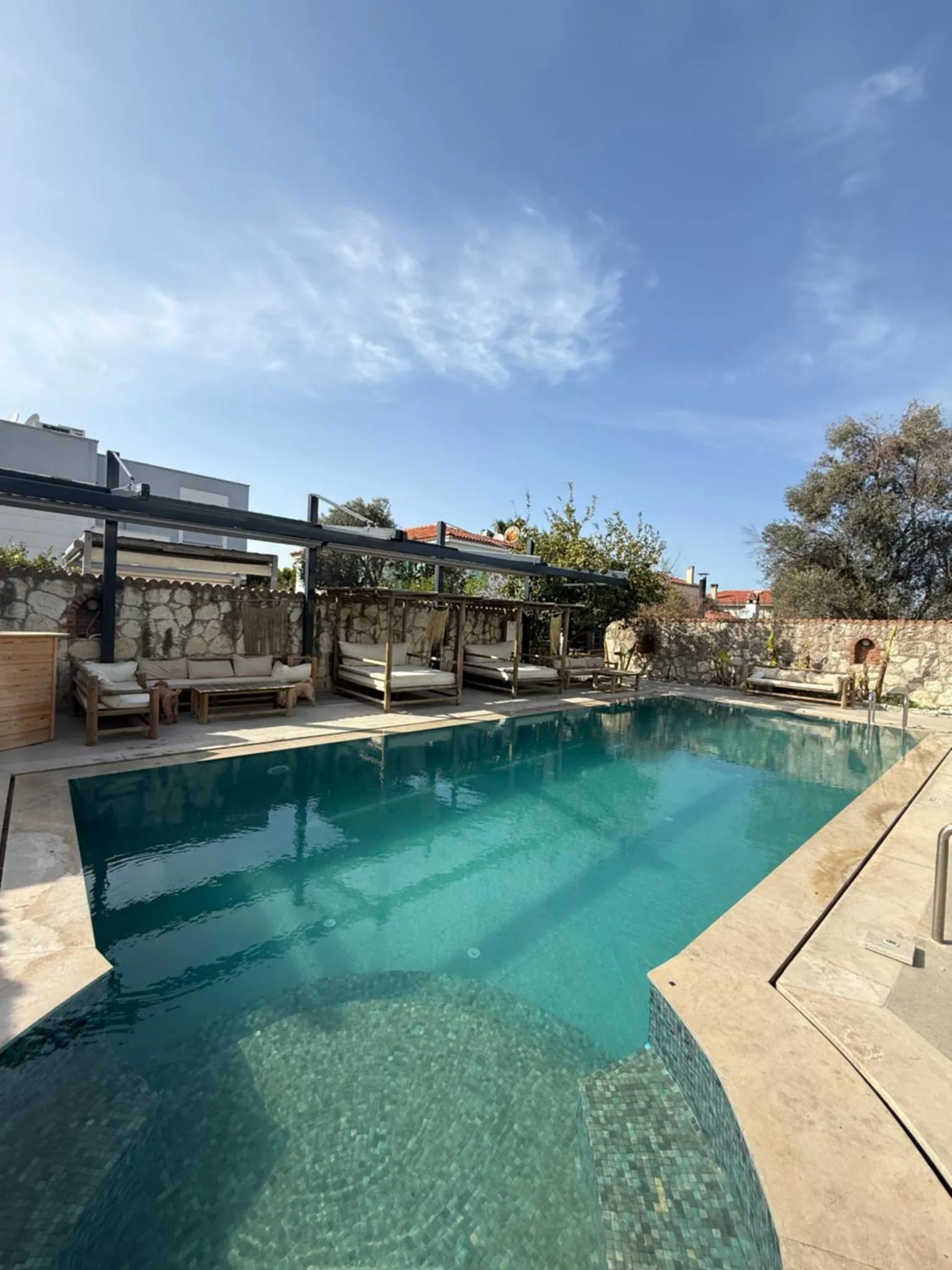 Une piscine rectangulaire turquoise bordée d'une terrasse avec des transats.