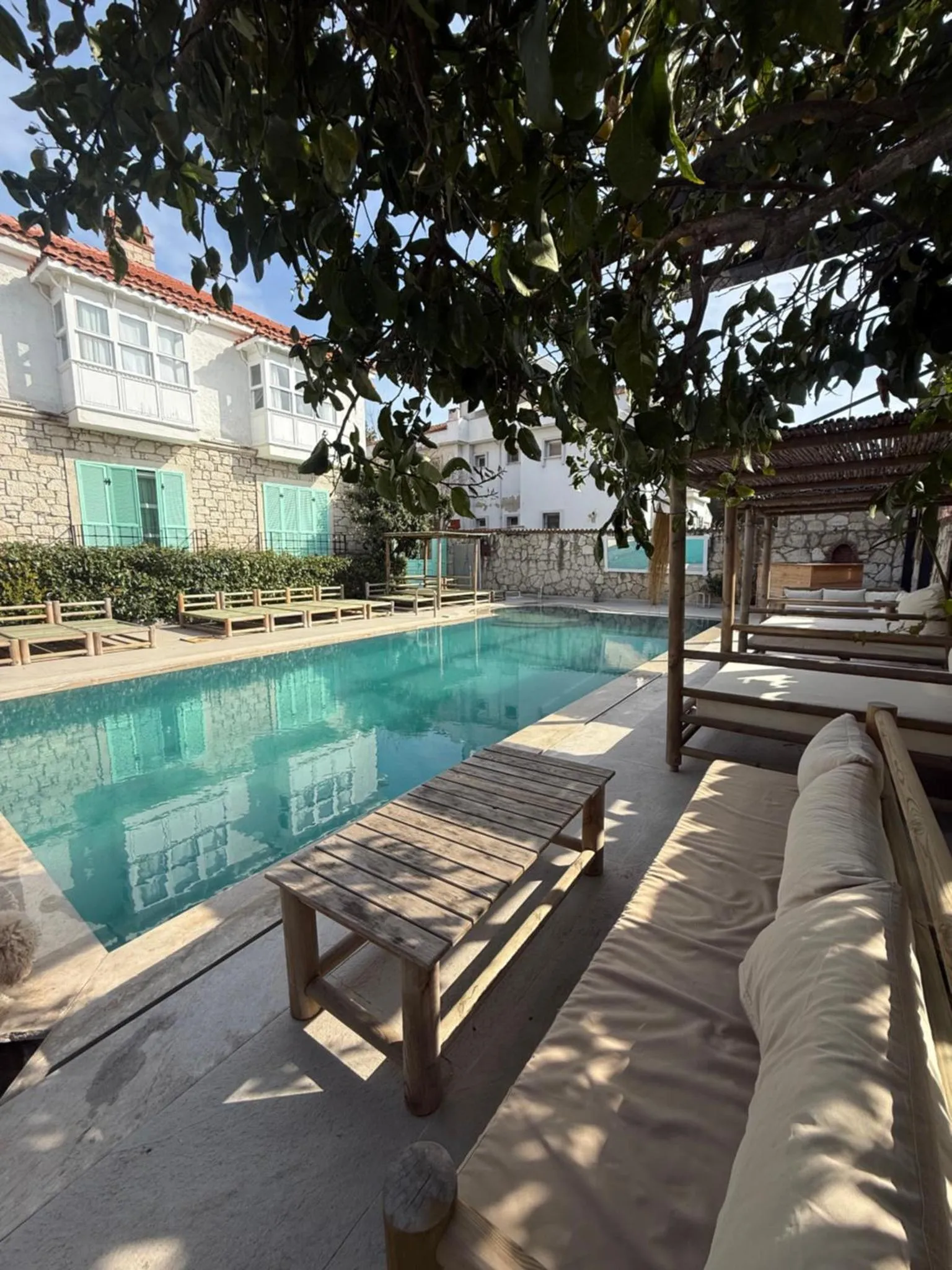Espace de détente extérieur avec piscine et mobilier de jardin ombragé.