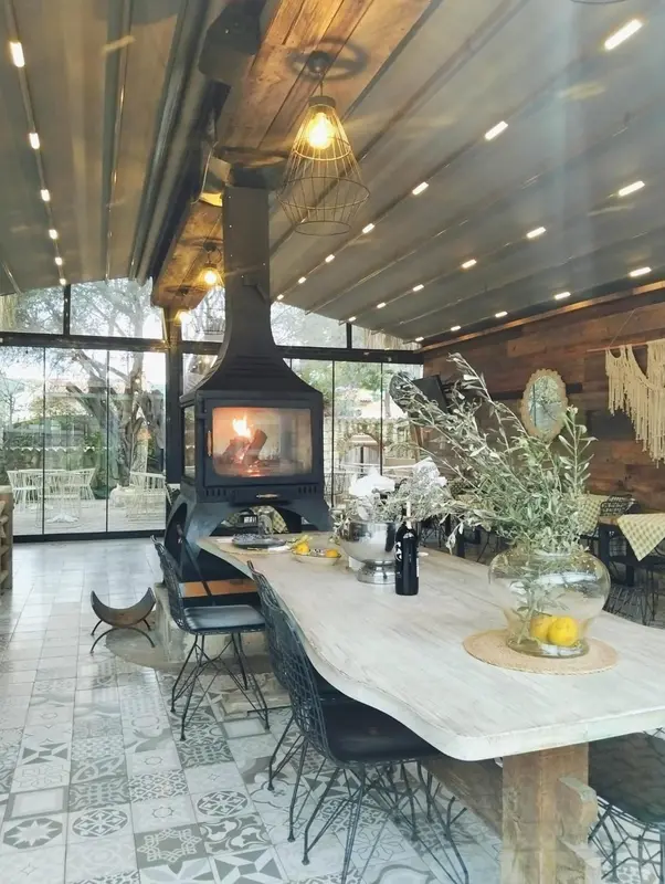 Une longue table en bois est mise en scène dans une salle à manger lumineuse avec une cheminée.
