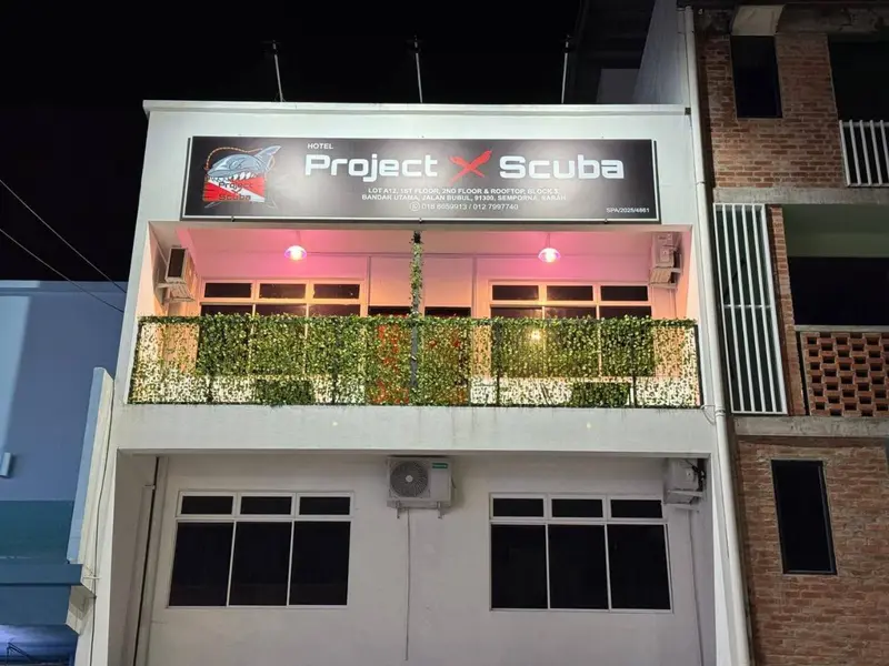 Façade d'un bâtiment avec une enseigne lumineuse et une végétation décorative.