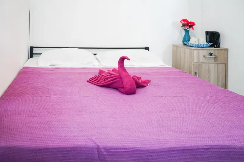 Lit double avec une couverture violette et une décoration en forme de cygne.