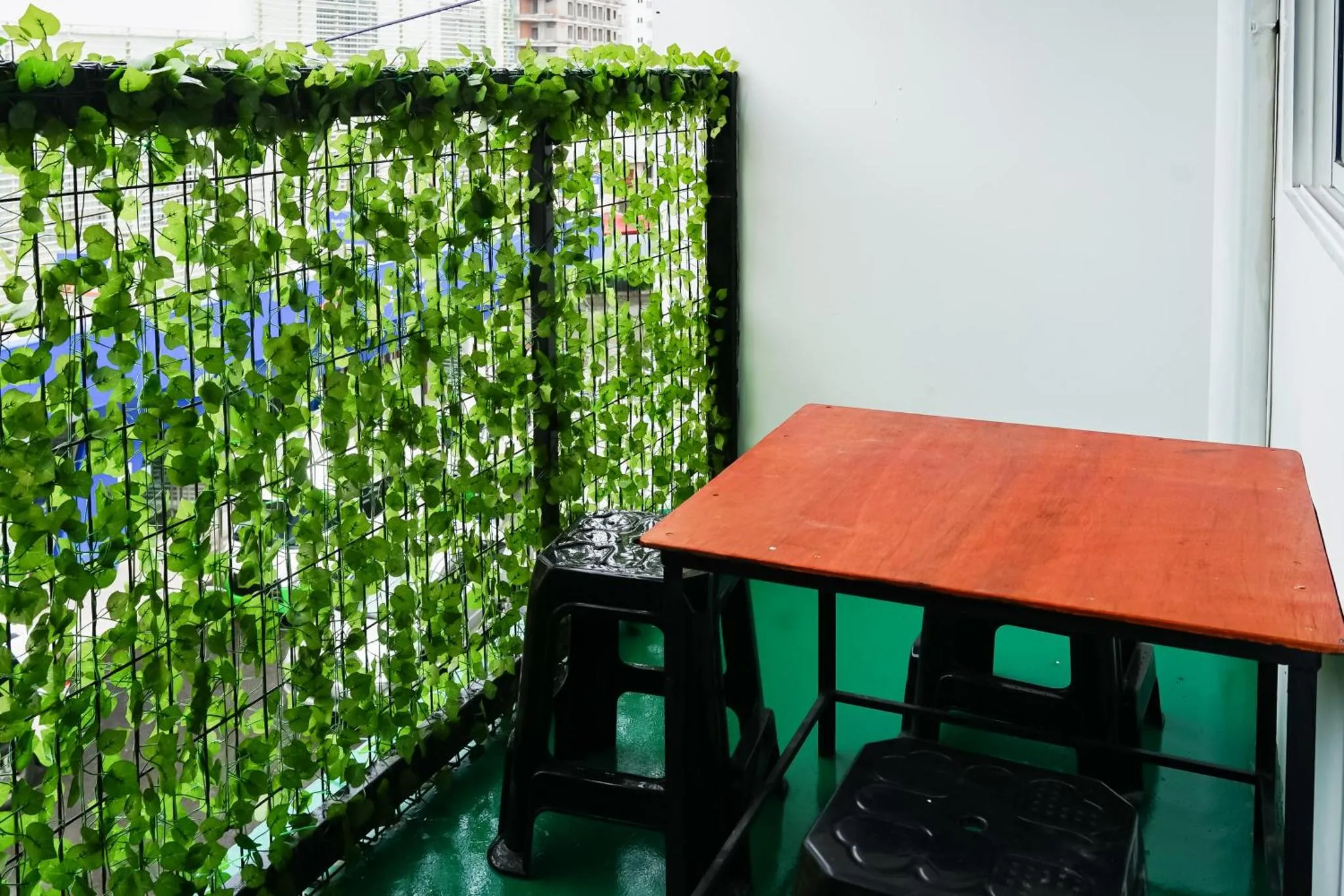 Une terrasse avec une table et des sièges devant un mur végétal.