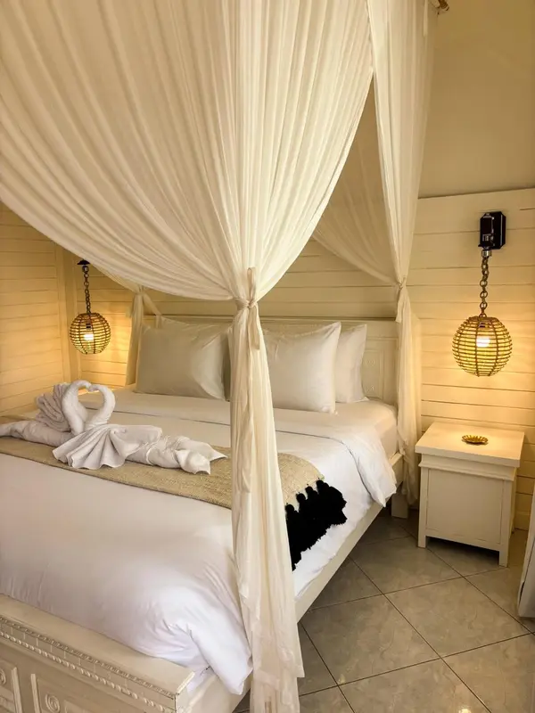 Un lit à baldaquin blanc est décoré de serviettes en forme de cygnes.