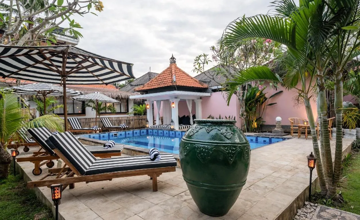 Transats rayés noirs et blancs disposés autour d'une piscine turquoise dans un jardin tropical.
