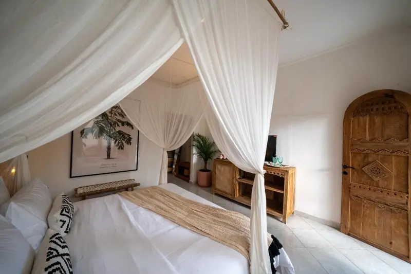 Un lit recouvert de moustiquaire dans une chambre lumineuse.