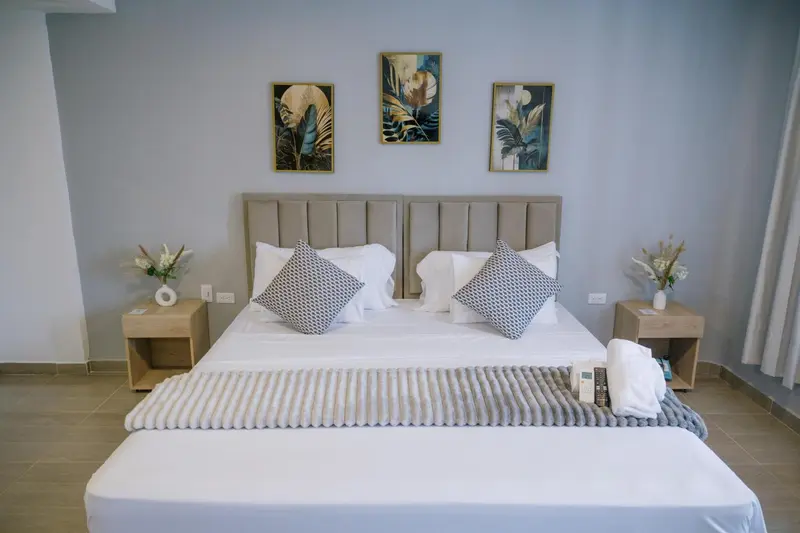 Une chambre lumineuse avec un grand lit et des tableaux décoratifs.