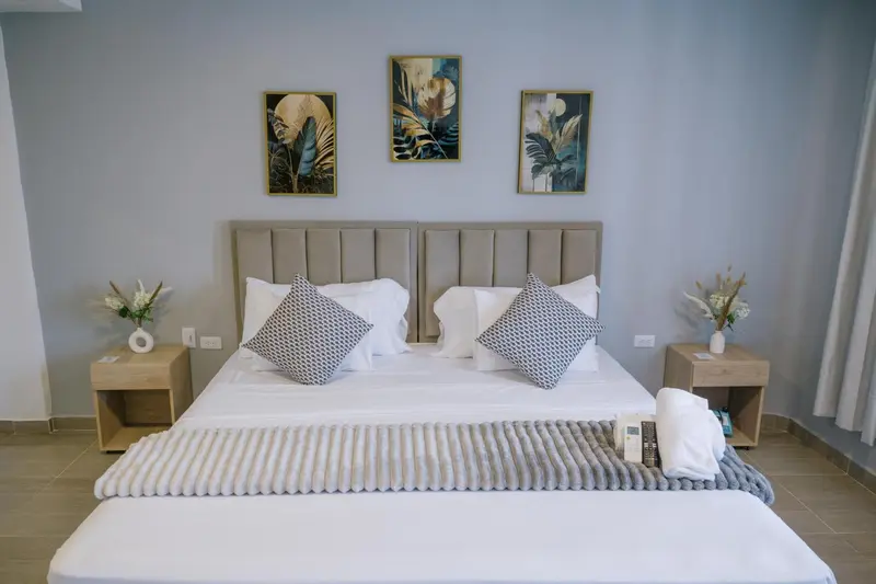 Un lit double avec des oreillers et une couverture est dispose dans une chambre.