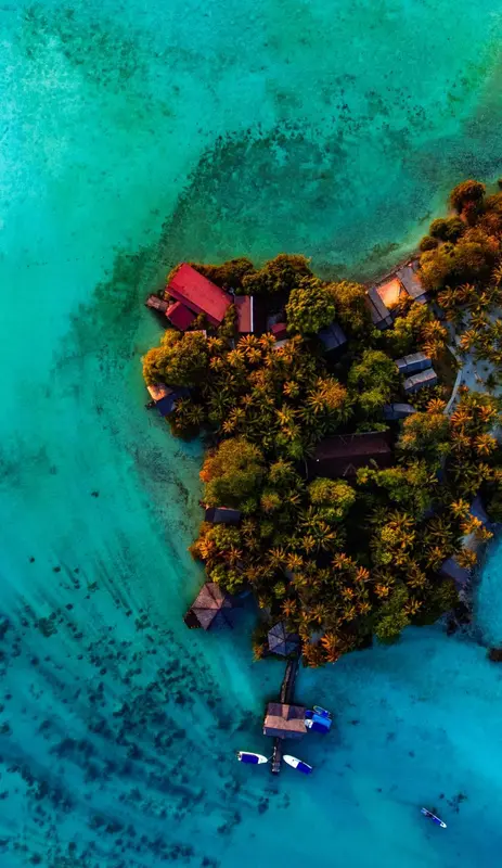 Vue aérienne d'un îlot tropical entouré d'eaux turquoise.