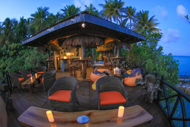 Terrasse en bois avec mobilier d'extérieur et bar en fond.