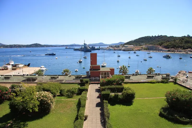 Vue d'un port de plaisance ensoleillé avec des bateaux et une végétation luxuriante.