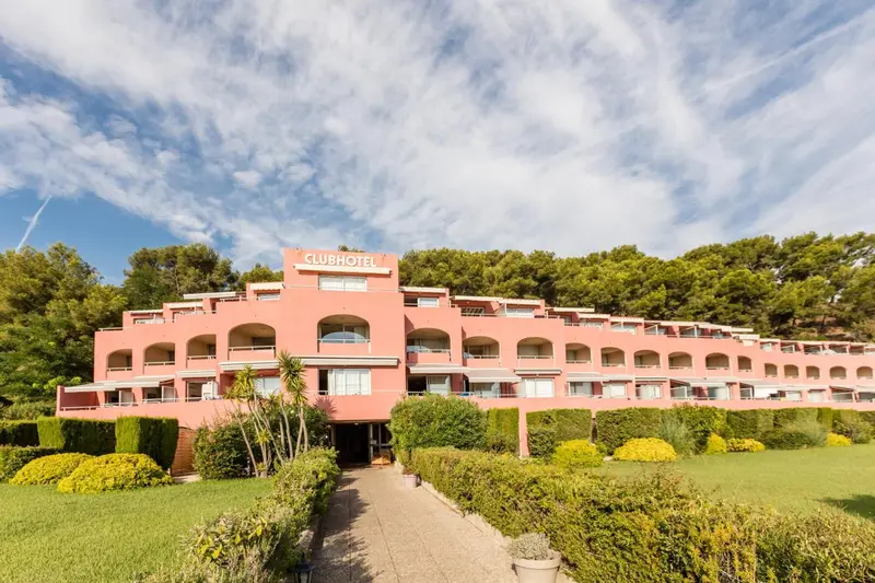 Bâtiment rose avec des balcons et une végétation luxuriante.