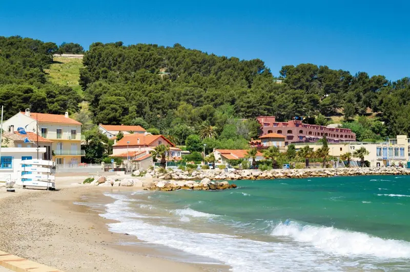 Vue d'une plage de galets bordée de bâtiments et de végétation.
