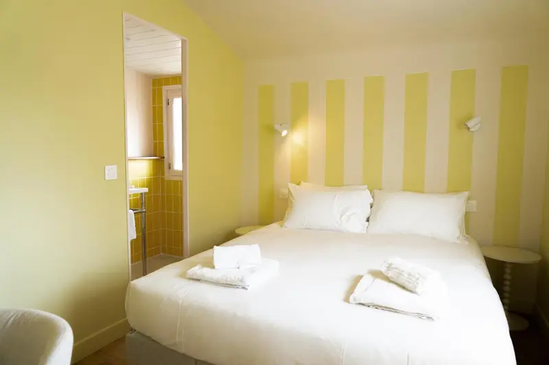 Une chambre lumineuse avec un lit recouvert d'une courtepointe blanche et des oreillers.