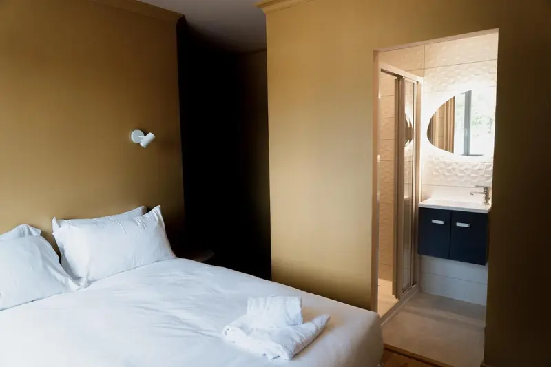 Une chambre lumineuse avec un lit blanc et une salle de bain moderne.