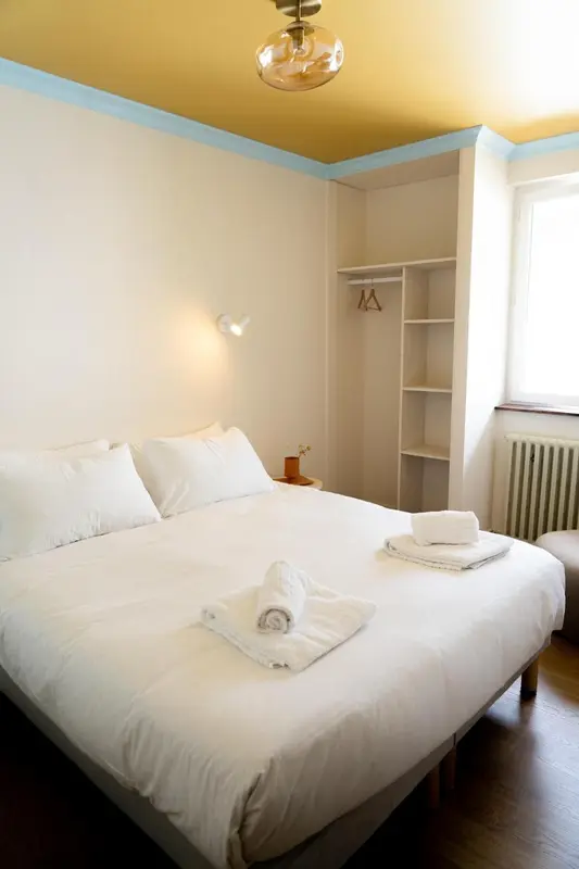 Une chambre lumineuse avec un lit fait et des serviettes.