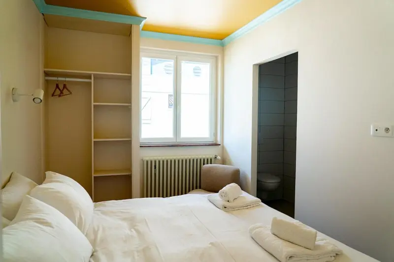 Une chambre lumineuse avec un lit fait et une salle de bain attenante.