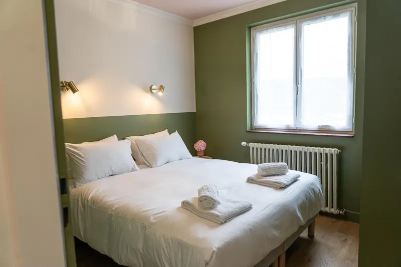 Une chambre lumineuse avec un lit fait et une fenêtre.