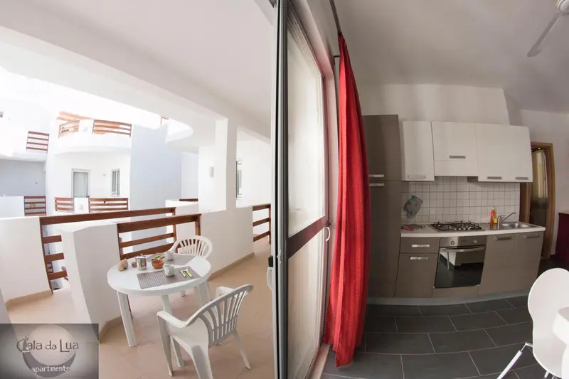 Une cuisine moderne s'ouvre sur un espace repas avec table et chaises sur une terrasse.