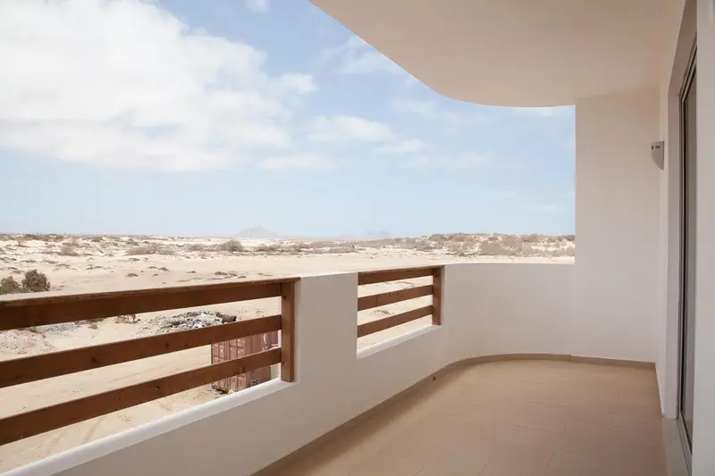 Balcon avec vue sur un paysage désertique et la mer.