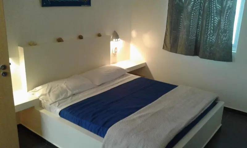 Une chambre lumineuse avec un lit recouvert d'une couverture bleue.