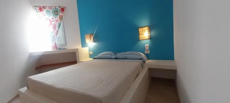 Une chambre lumineuse avec un lit double et un mur bleu vif.
