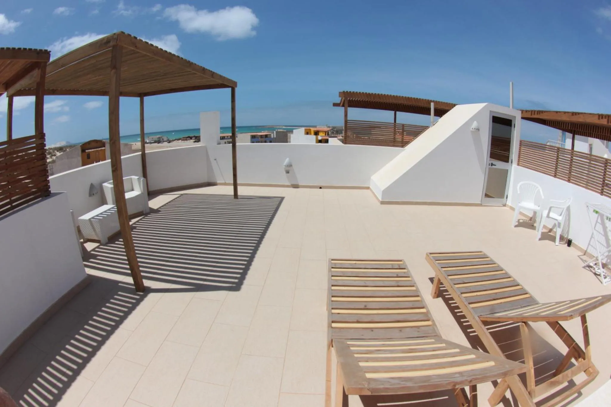 Terrasse ensoleillée avec mobilier de détente et vue sur la mer.