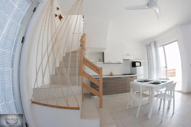 Une cuisine lumineuse s'ouvre sur un espace repas et un escalier décoratif.