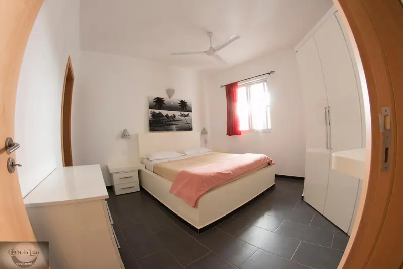 Chambre lumineuse avec un grand lit et une décoration sobre.