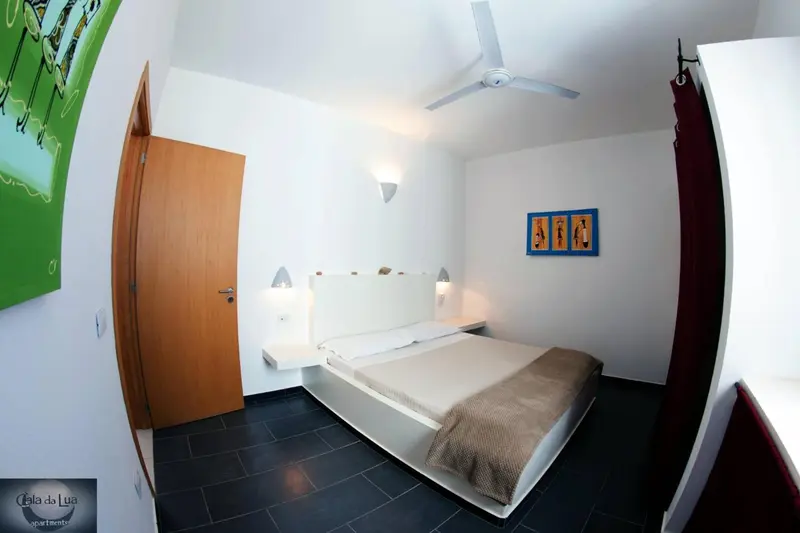 Une chambre lumineuse avec un lit double et un décor mural coloré.