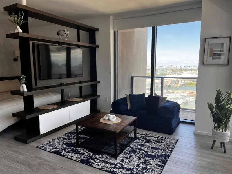 Un salon moderne avec un canapé bleu et une grande fenêtre offrant une vue sur la ville.