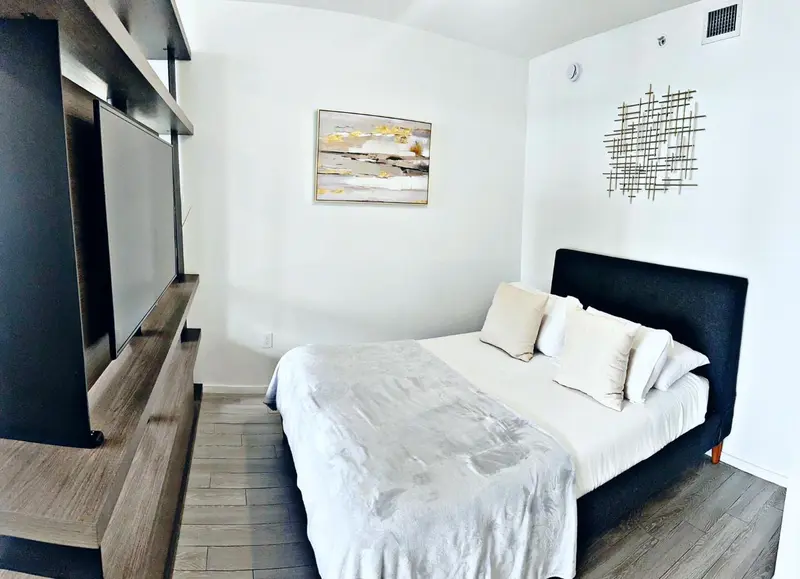 Une chambre lumineuse avec un grand lit et une télévision murale.