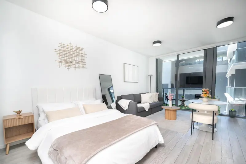 Espace de vie lumineux avec un lit et un coin salon près d'une fenêtre.