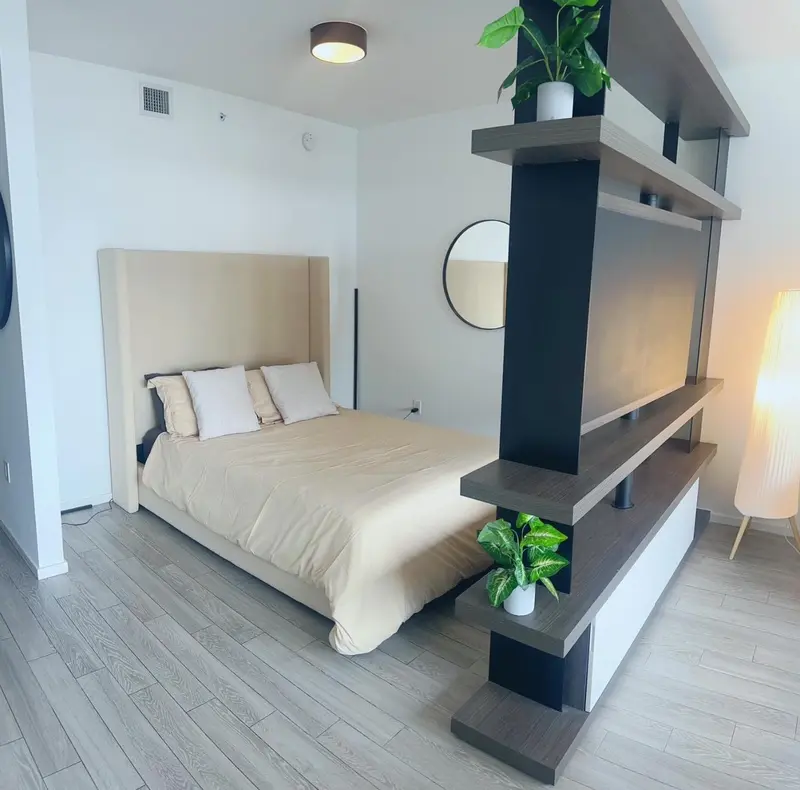 Une chambre lumineuse avec un grand lit et un séparateur de pièce en bois.