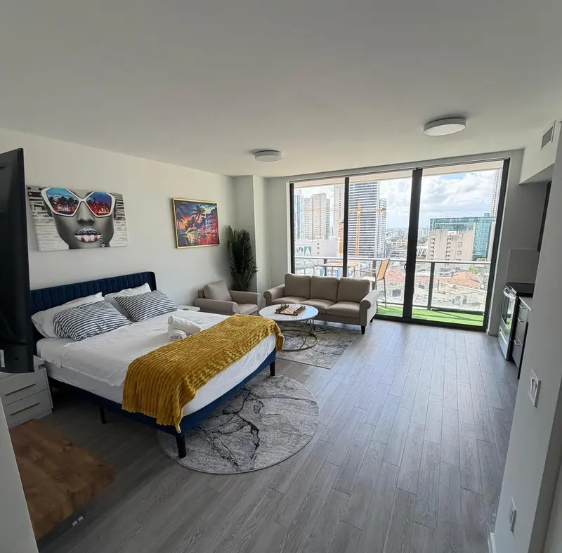 Une chambre lumineuse avec un grand lit et un canapé face à une baie vitrée.