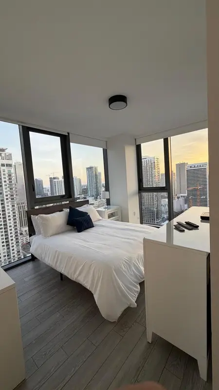 Une chambre lumineuse avec un grand lit et une vue sur la ville.
