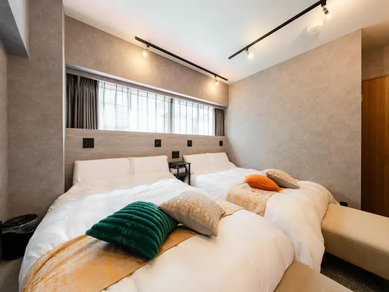 Une chambre lumineuse avec un grand lit recouvert de coussins et de couvertures.