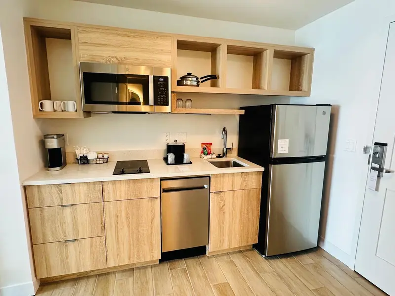 Une kitchenette moderne avec des appareils en acier inoxydable et des armoires en bois clair.